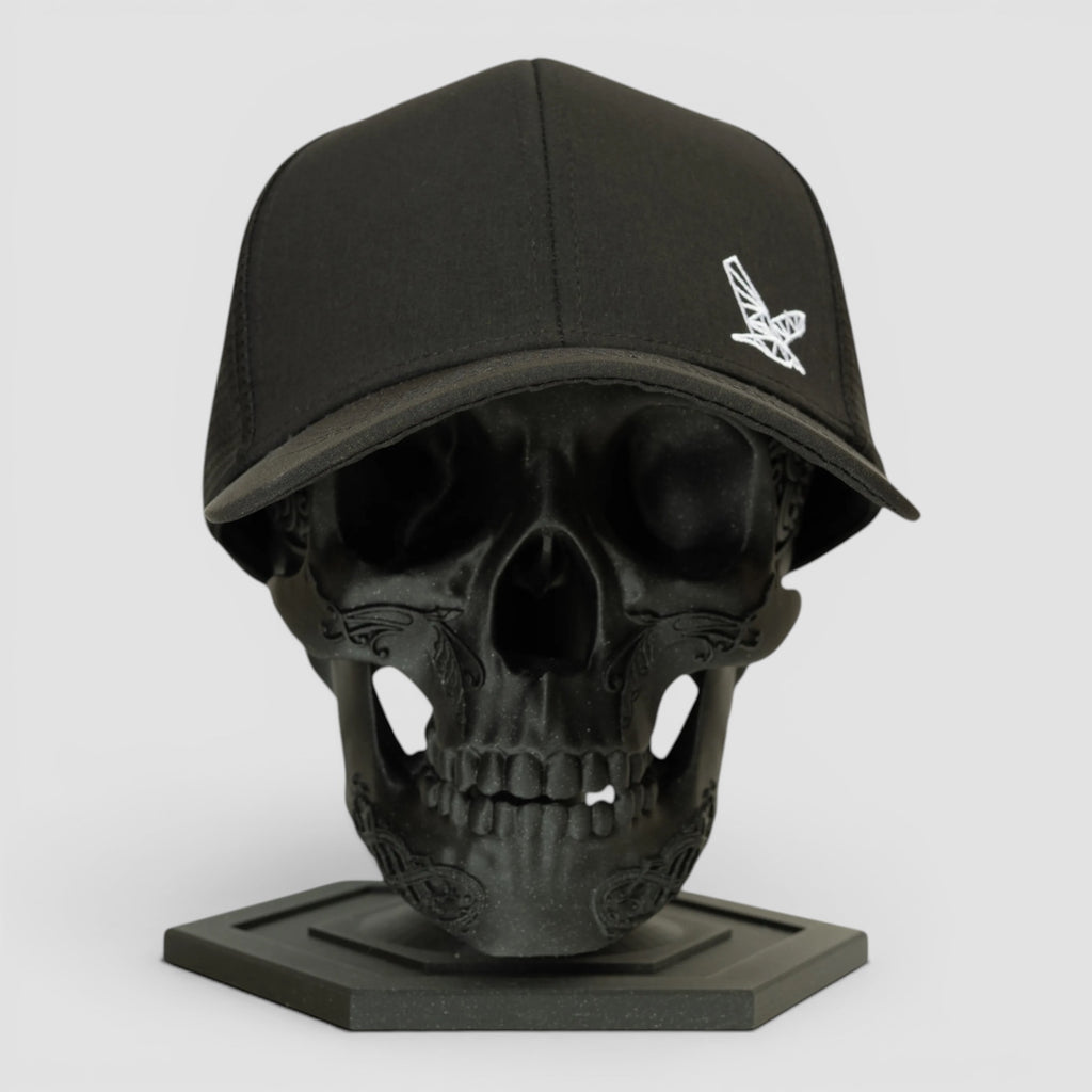 Night Heron Israel black baseball cap with white embroidered logo on a black skull display stand