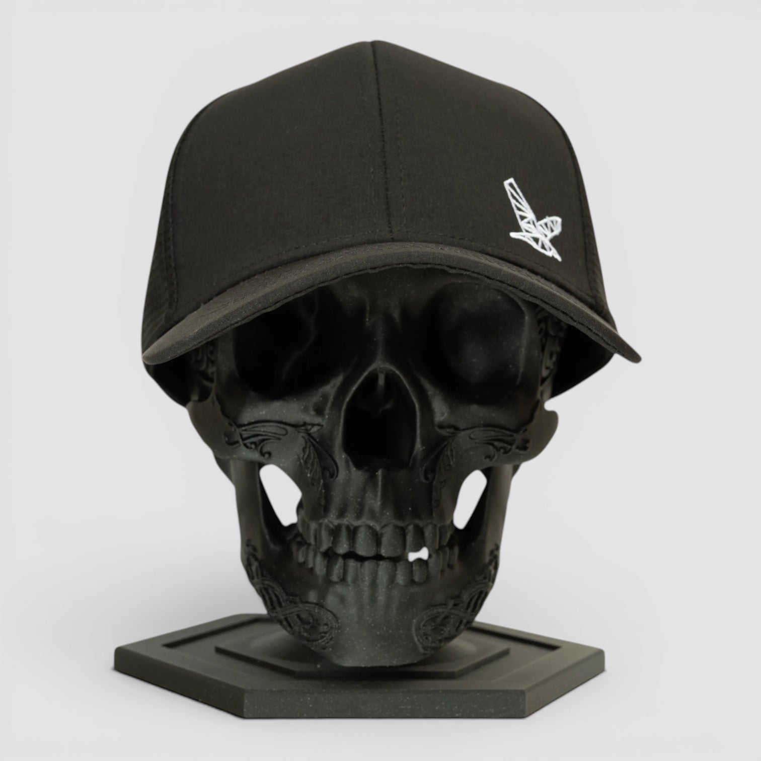 Night Heron Israel black baseball cap with white embroidered logo on a black skull display stand