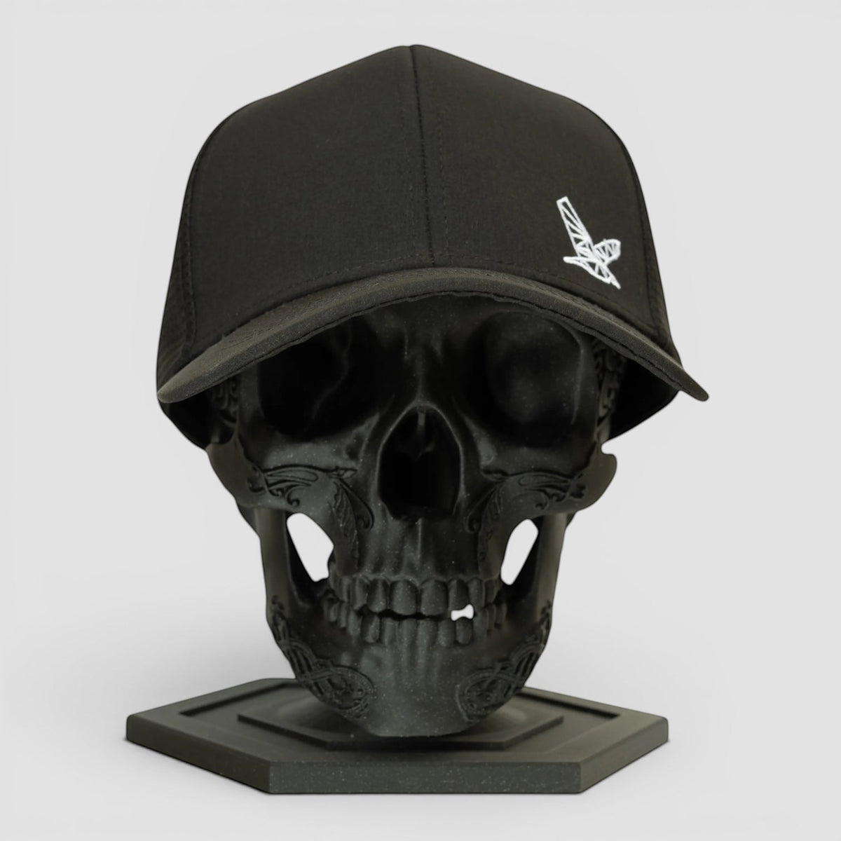 Night Heron Israel black baseball cap with white embroidered logo on a black skull display stand