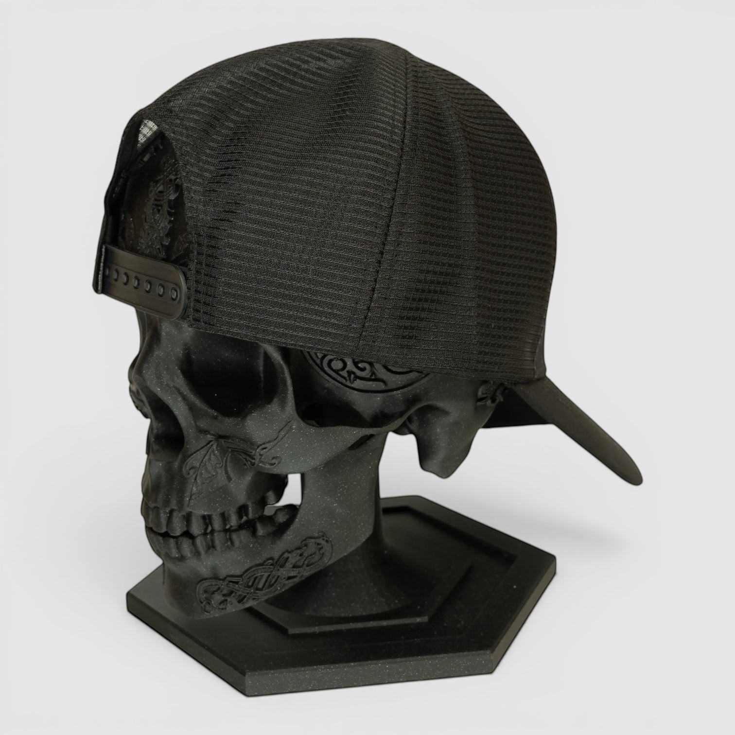 Night Heron Israel black mesh trucker cap displayed on a decorative black skull head stand
